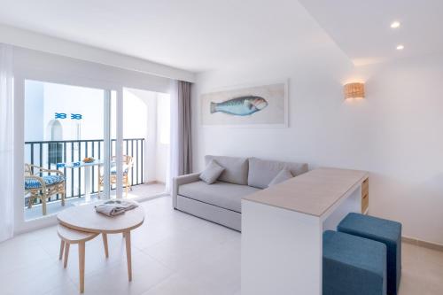 a living room with a couch and a table at FERGUS Style Carema Beach in Cala en Bosc