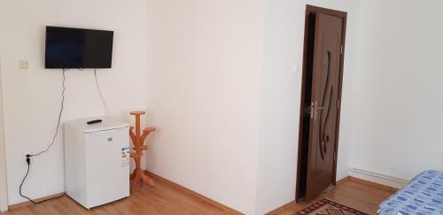 een kamer met een koelkast en een televisie aan de muur bij Korondi Pisztrangos in Corund