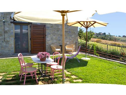 カスティリオーネ・デル・ラーゴにあるCasa Gioielloのテーブルと椅子と傘のあるパティオ