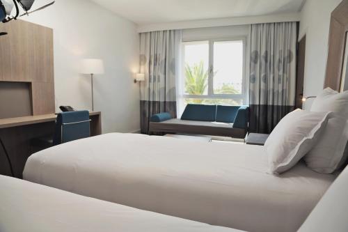 a hotel room with two beds and a couch at Novotel Mohammedia in Mohammedia