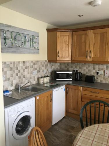 a kitchen with a sink and a washing machine at Old Mill Cottage in Swinford