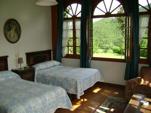 a bedroom with two beds and a large window at Hotel Rural La Lastra in Caso
