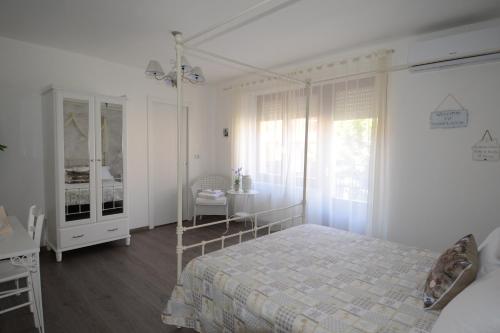 a white bedroom with a bed and a table at Terry's House in Nuoro