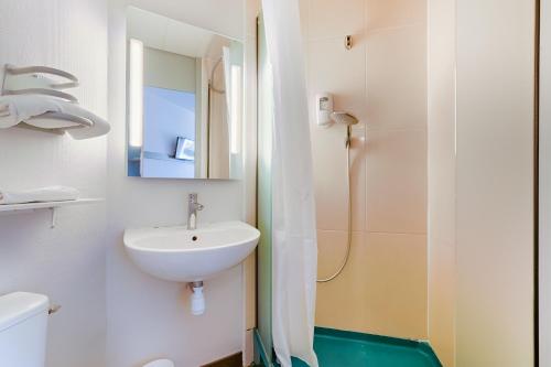 ein weißes Bad mit einem Waschbecken und einer Dusche in der Unterkunft B&B HOTEL Aix-en-Provence Pont de l'Arc in Aix-en-Provence