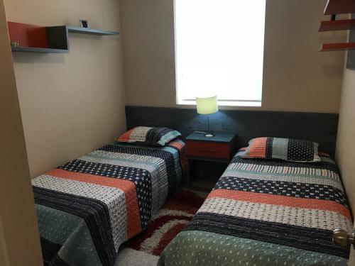 2 camas en una habitación pequeña con ventana en Laguna Bahía Algarrobo, en Algarrobo