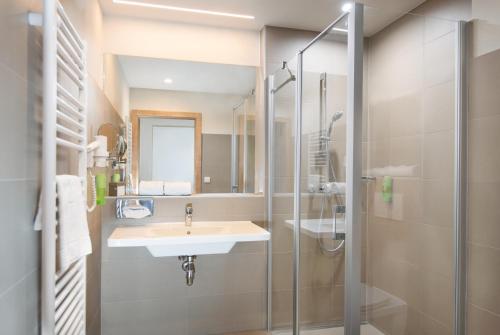 een badkamer met een wastafel en een douche bij JUFA Hotel Neutal in Neutal