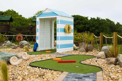 ein kleines Spielhaus in einem Garten mit einer Minigolfanlage in der Unterkunft Whitecliff Bay Holiday Park in Bembridge