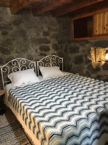 Bett in einem Zimmer mit einer Steinmauer in der Unterkunft A Casa do Avô Coelho in Santo Antão