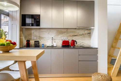 a kitchen with white cabinets and a wooden table at Formosa 168 by Guestify in Porto