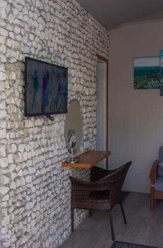 a room with a stone wall with a table and a chair at Sandy Heaven Maldives in Gulhi
