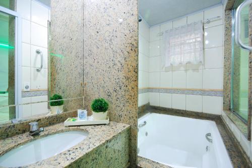 a bathroom with a tub and a sink at Mirage Motel Guarulhos in Sao Paulo