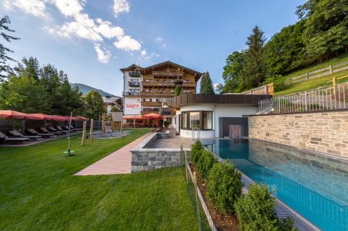 a resort with a swimming pool and a building at Hotel Babymio in Kirchdorf in Tirol