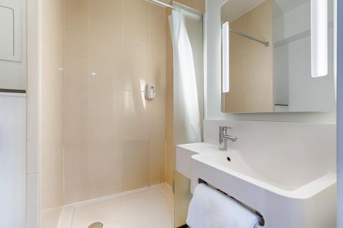 een witte badkamer met een wastafel en een douche bij B&B HOTEL Marseille Centre La Joliette in Marseille