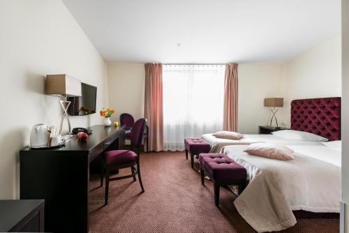 a hotel room with two beds and a desk at Amberton Cathedral Square Hotel Vilnius in Vilnius