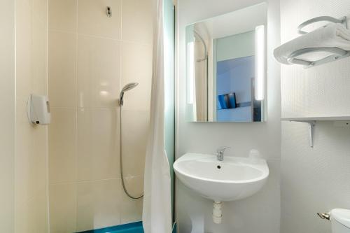 La salle de bains blanche est pourvue d'un lavabo et d'une douche. dans l'établissement B&B HOTEL Marseille Estaque, à Marseille