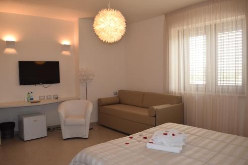 um quarto com uma cama, um sofá e uma televisão em Masseria Corte Masseriola em Alberobello