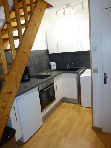 een keuken met witte kasten en een houten vloer bij Les Galets in Dieppe