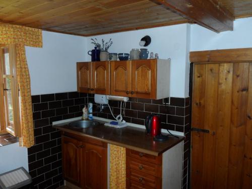 a kitchen with a sink and black tiles on the wall at Stylová chalupa na kraji národního parku Šumava in Strunkov