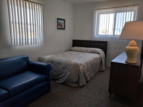 a bedroom with a bed and a chair and a lamp at Tide Winds Motel in Wildwood