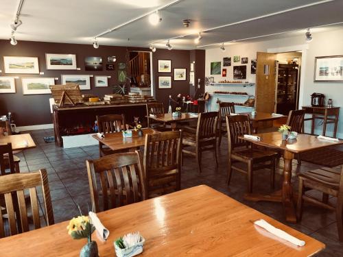 comedor con mesas y sillas de madera en The Water's Edge Inn & Gallery en Baddeck