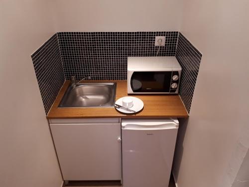 a small kitchen with a sink and a microwave at Hôtel Résidence Champerret in Levallois-Perret
