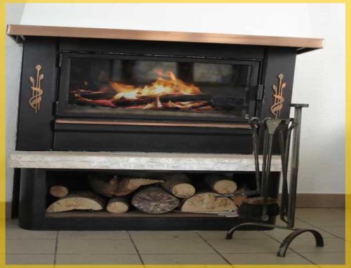 a fireplace with logs and a fire in it at Gîte Les Hirondelles in Plombières-les-Bains