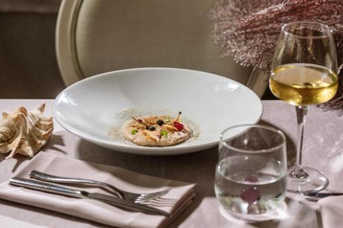 a plate of food and a glass of wine on a table at Baia del Mar Beach Boutique Hotel in Lido di Jesolo