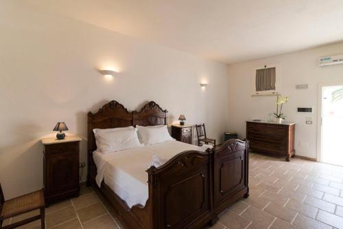 a bedroom with a large wooden bed with white sheets at Masseria Carignani in Tuglie