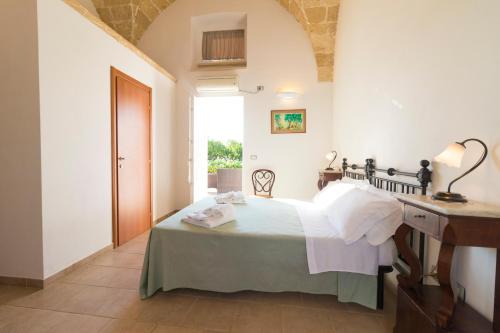 a bedroom with a bed and a desk and a window at Masseria Carignani in Tuglie