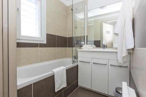 uma casa de banho com uma banheira branca e um lavatório. em Résidence Club Odalys Les Villas de Bel Godère em Belgodère