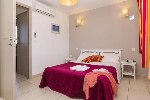 um quarto com uma cama com um cobertor vermelho em Résidence Club Odalys Les Villas de Bel Godère em Belgodère