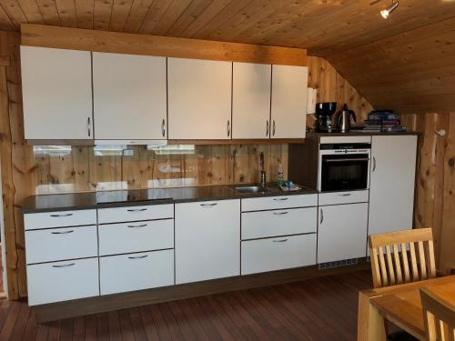 a kitchen with white cabinets and a wooden ceiling at Nordkappferie in Gjesvær