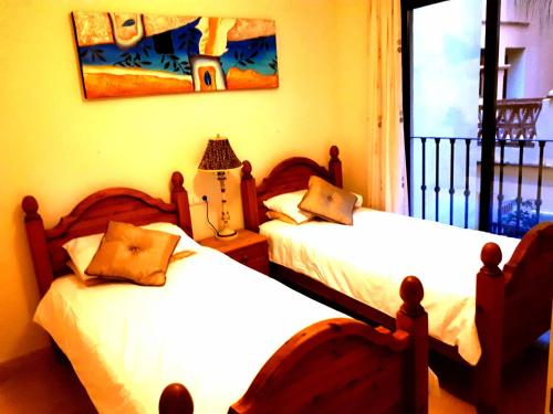 ラ・カラ・デ・ミハスにあるJardines de La Noriaのベッドルーム1室(ベッド2台、窓付)