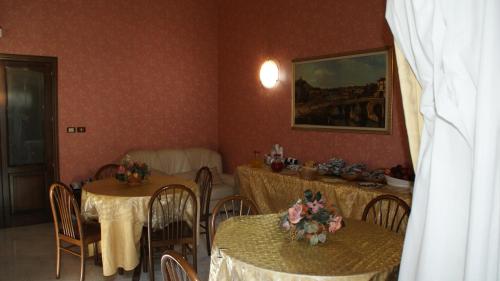 pokój z dwoma stołami i krzesłami z kwiatami w obiekcie Hotel Gresi w Katanii