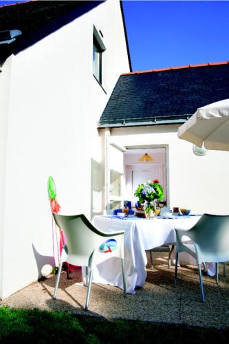 une table et des chaises devant une maison blanche dans l'établissement Village Club Goelia Les Voiles blanches, à Batz-sur-Mer