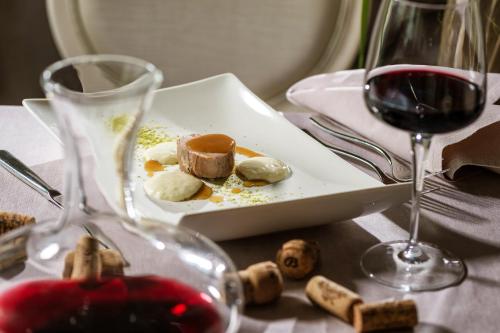 a plate of food and a glass of wine on a table at Baia del Mar Beach Boutique Hotel in Lido di Jesolo