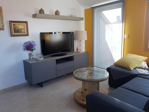 sala de estar con TV, sofá y mesa en La Xouba en Rianjo