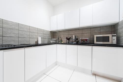 a white kitchen with white cabinets and a microwave at Grosvenor Suites in Edinburgh