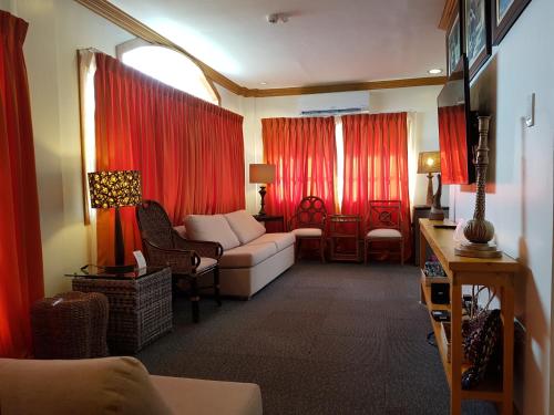 een woonkamer met een bank en rode gordijnen bij Stay Amare Pacific Grand Magnolia in Mactan