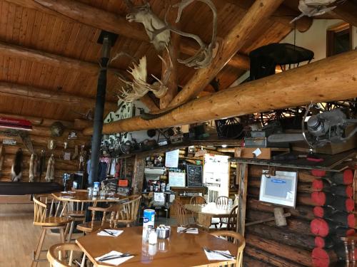 a restaurant with tables and chairs and wooden ceilings at Lake Louise Lodge, Alaska in Glennallen