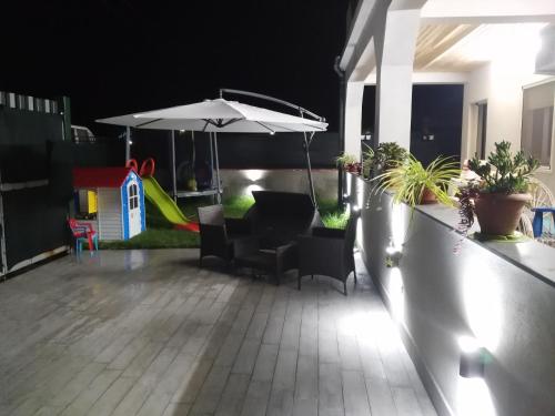 balcón con sombrilla y sillas y parque infantil en Villa Andrea, en Catania