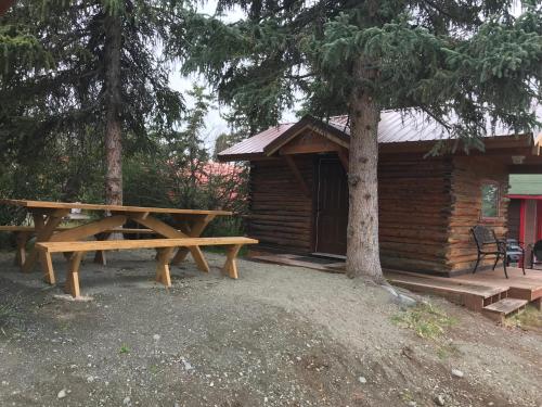 a picnic table in front of a log cabin at Lake Louise Lodge, Alaska in Glennallen