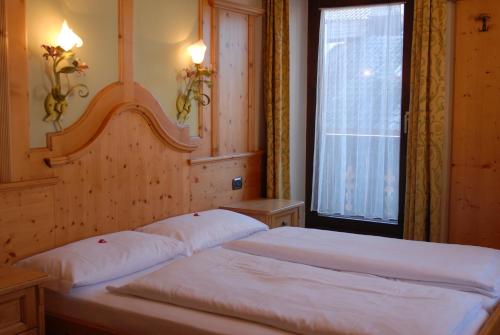 2 Betten in einem Schlafzimmer mit Fenster in der Unterkunft Hotel Loewenwirt in Sexten