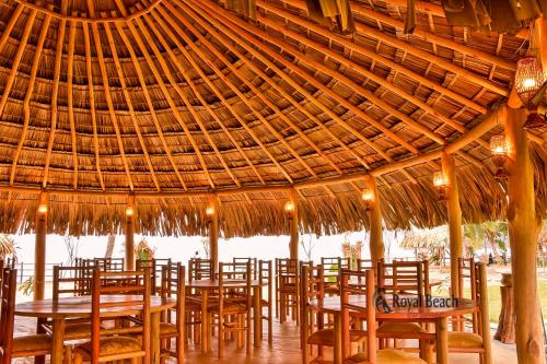 a group of tables and chairs under a large straw umbrella at Royal Beach in Arugam Bay