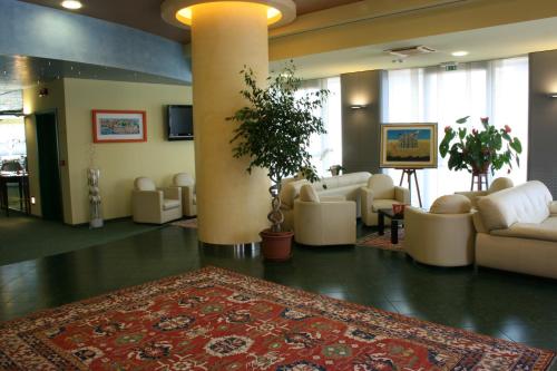 a lobby with white furniture and a rug on the floor at Hotel Senator in Gorgonzola