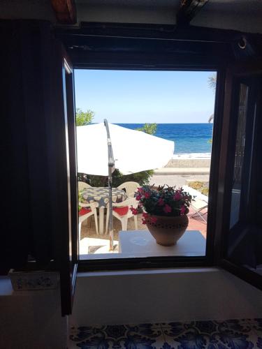 una ventana con vistas a la playa con un jarrón de flores en Stromboli Vacanze, en Stromboli