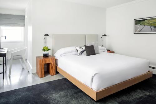 a white bedroom with a large bed and a desk at Bluebird Spa City Motor Lodge in Saratoga Springs