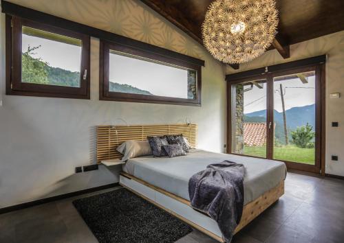 a bedroom with a bed with a chandelier and windows at Cal Sadurní in Bruguera