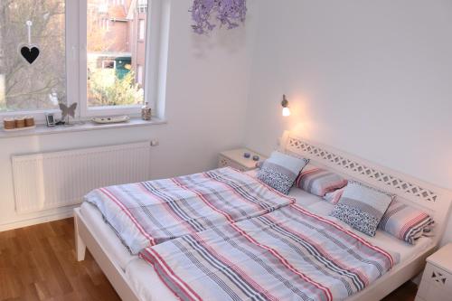 ホールマージールにあるNordseestrandの白いベッドルーム(枕付きのベッド、窓付)