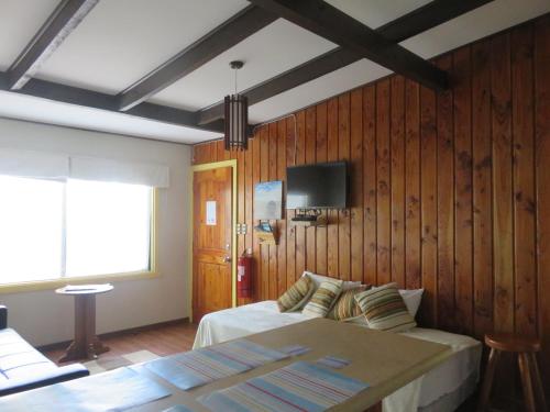a bedroom with a bed and a tv on a wooden wall at Cabañas Donde La Oma in Villarrica